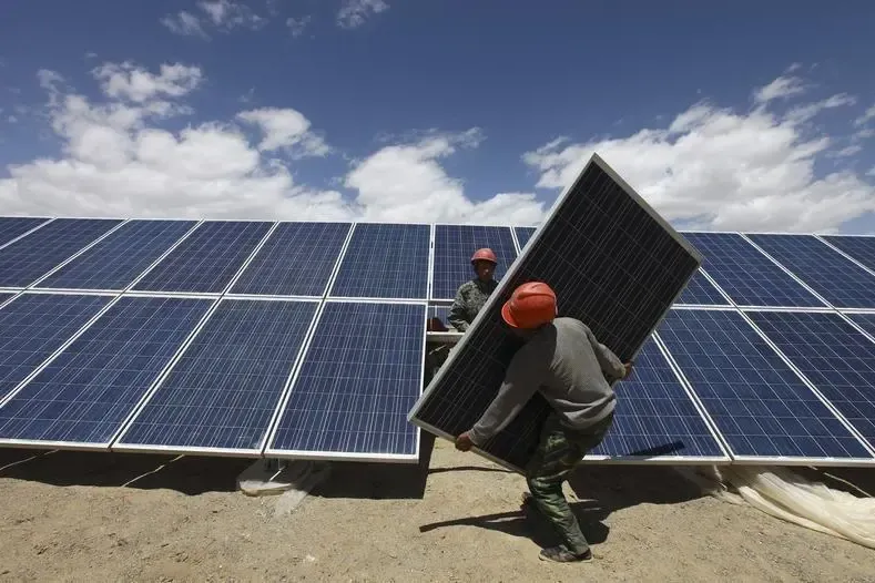 Workers installing solar panel in field
